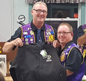 Lion Dean Sampson accepts a Lions jacket in appreciation of his work with the Lions Club from King Lion Barry LeBlanc.