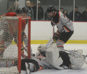 Islander goalie Ewan MacDonald covers the puck while Keenan Gillis (standing) and Logan Chisholm add assistance. 